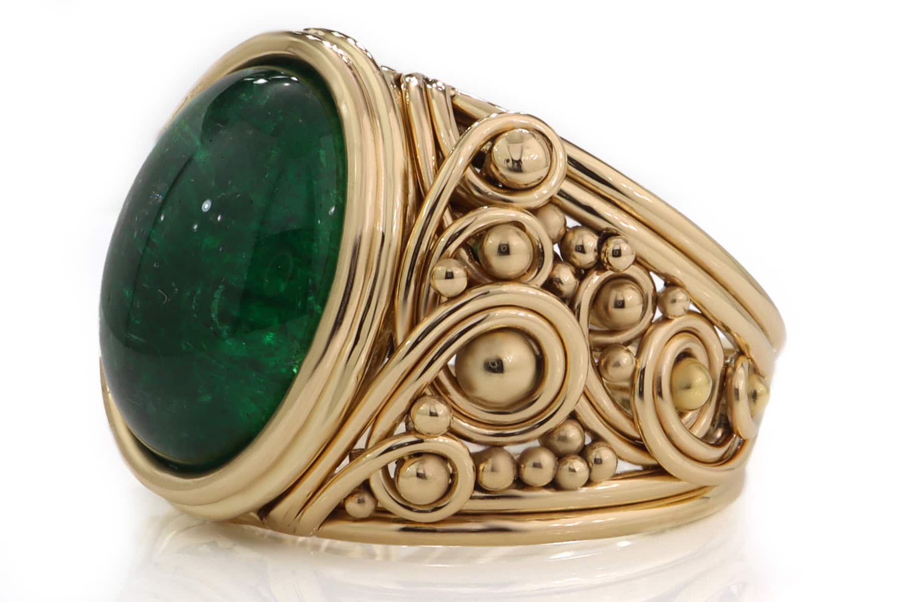 Gold ring featuring a large green gemstone and intricate wirework design.