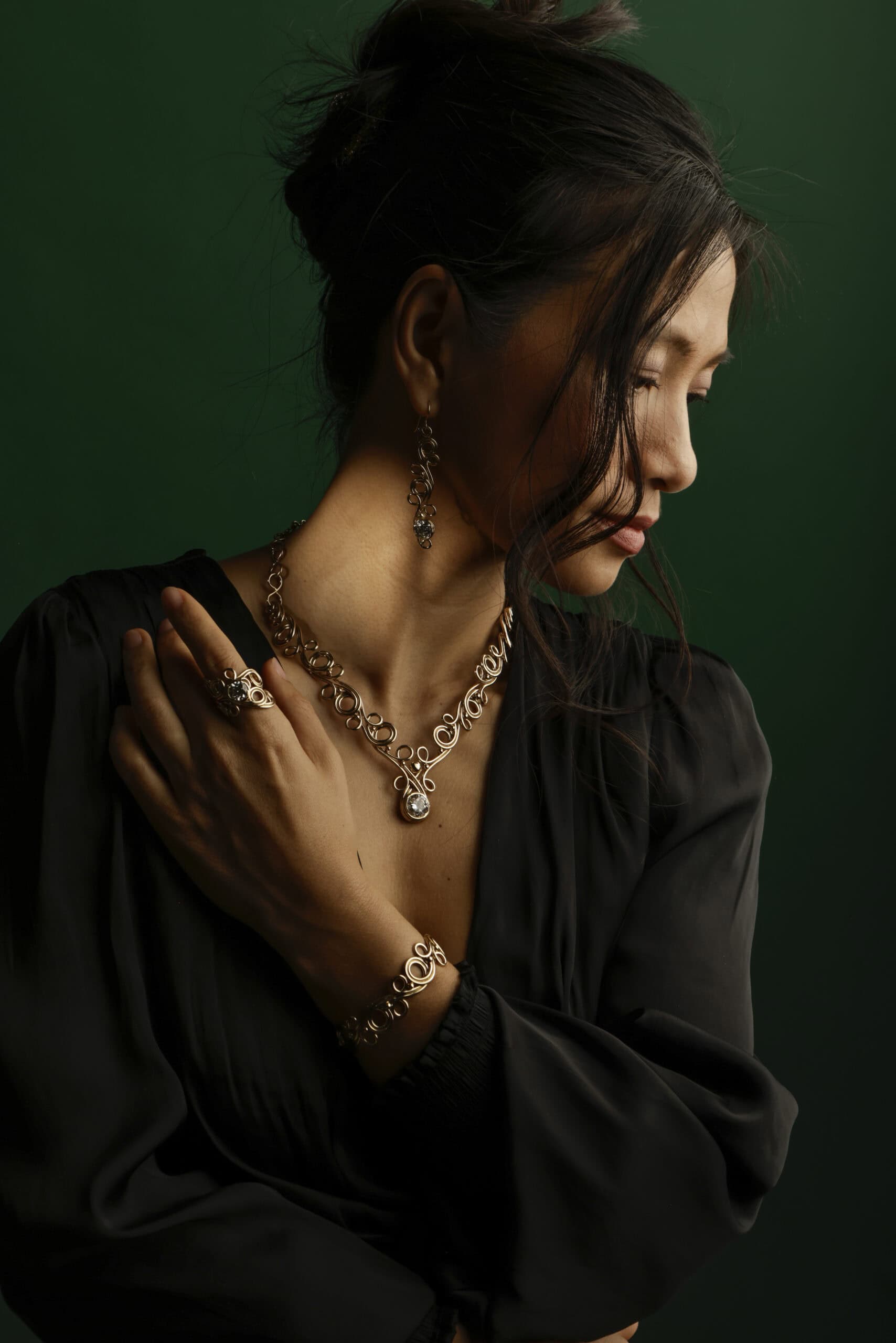 Woman wearing elegant jewelry against dark green background.
