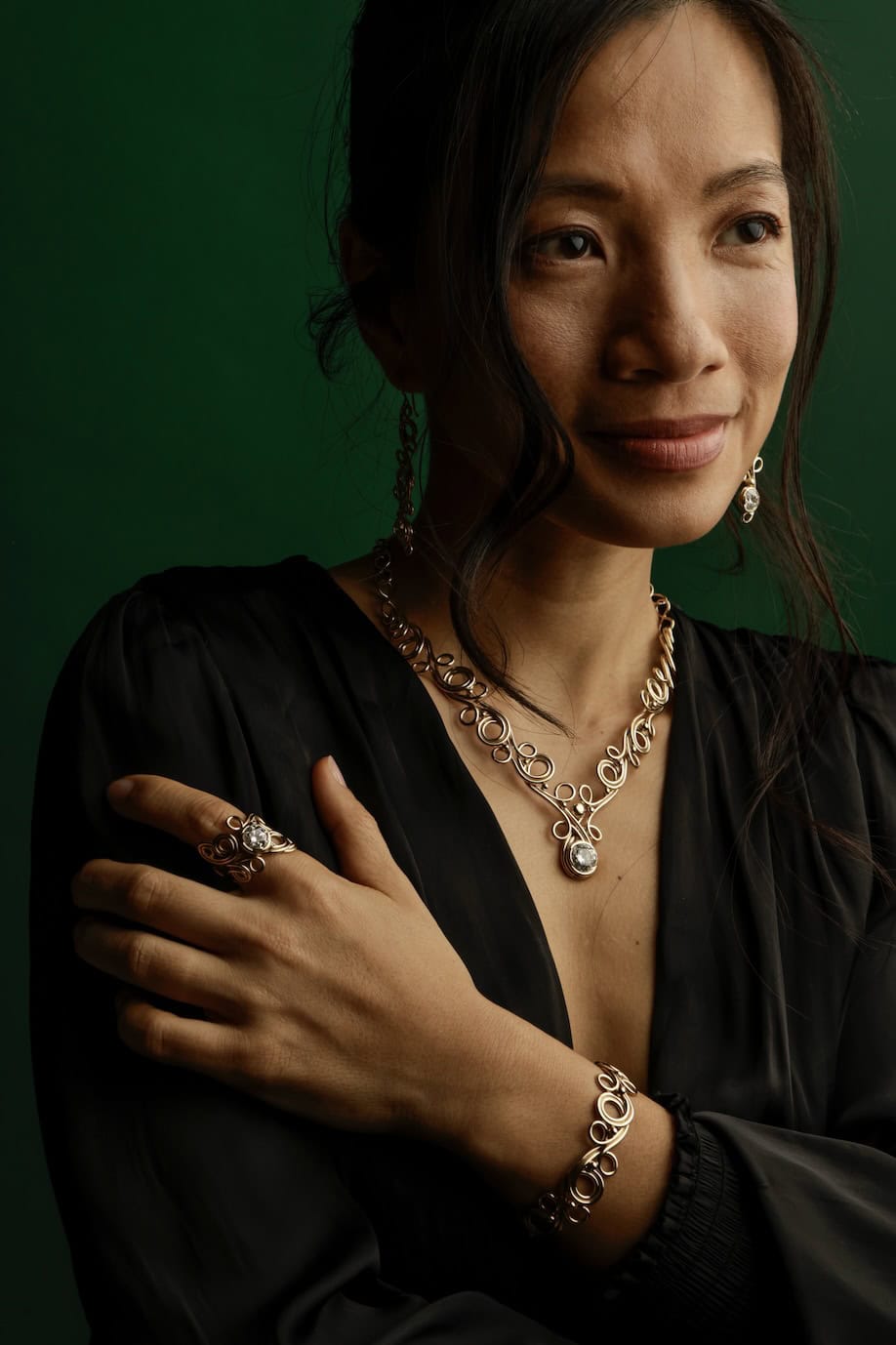 Portrait of a woman wearing jewelry against a green background.